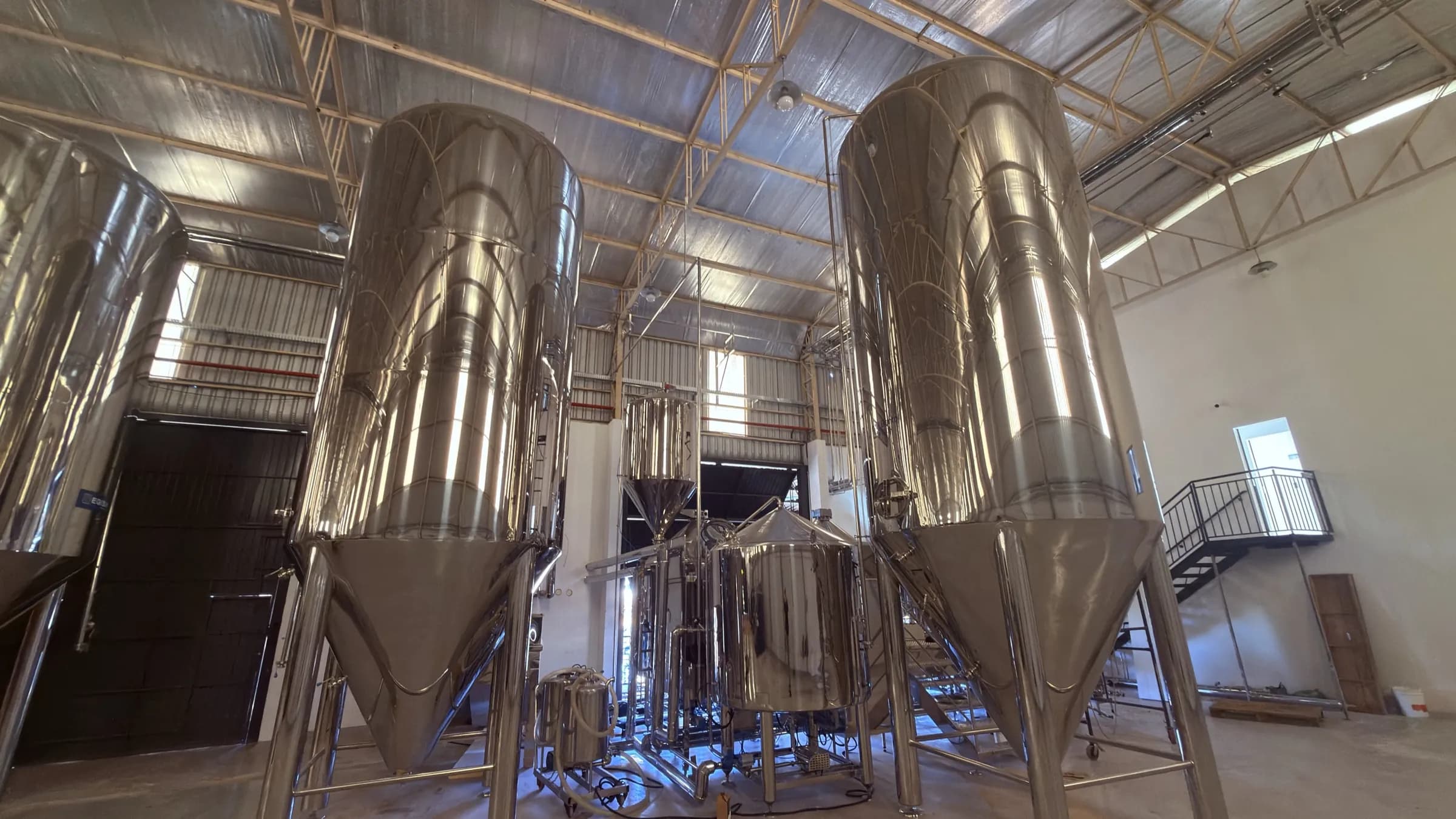 Fermentadores de inox dentro do galpão da IMDM, onde o chopp com a marca do parceiro é produzido